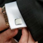 Man fastening cufflink on suit sleeve