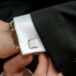 Person adjusting cufflink on suit sleeve