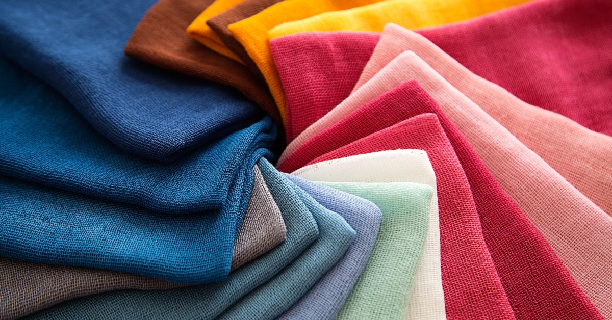 Cotton fabric swatches in various colors lying neatly stacked on a surface, showing textures and patterns.