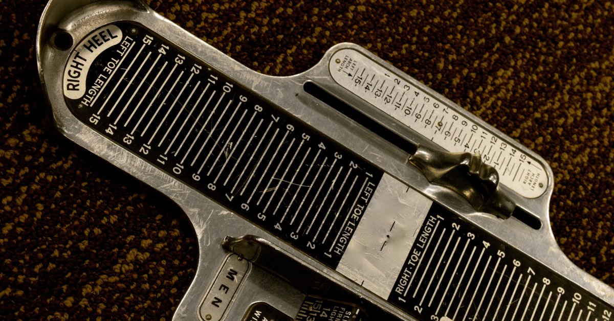 A metal foot measuring tool sitting on a display, ready to determine accurate shoe sizes with precise markings.